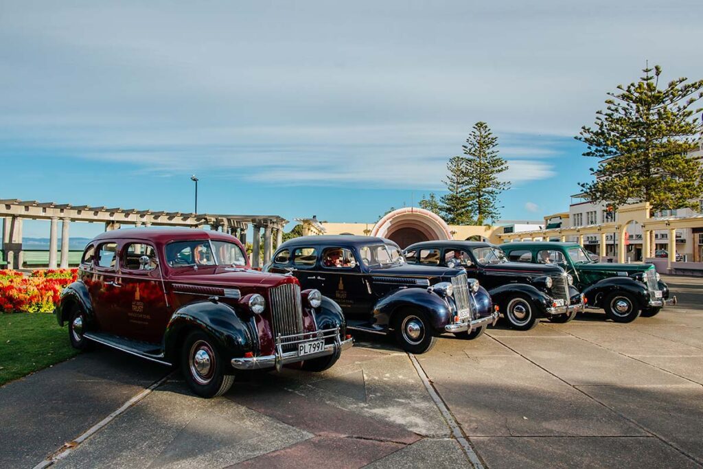 Four vintage cars are parked in a row with a blue sky behind them